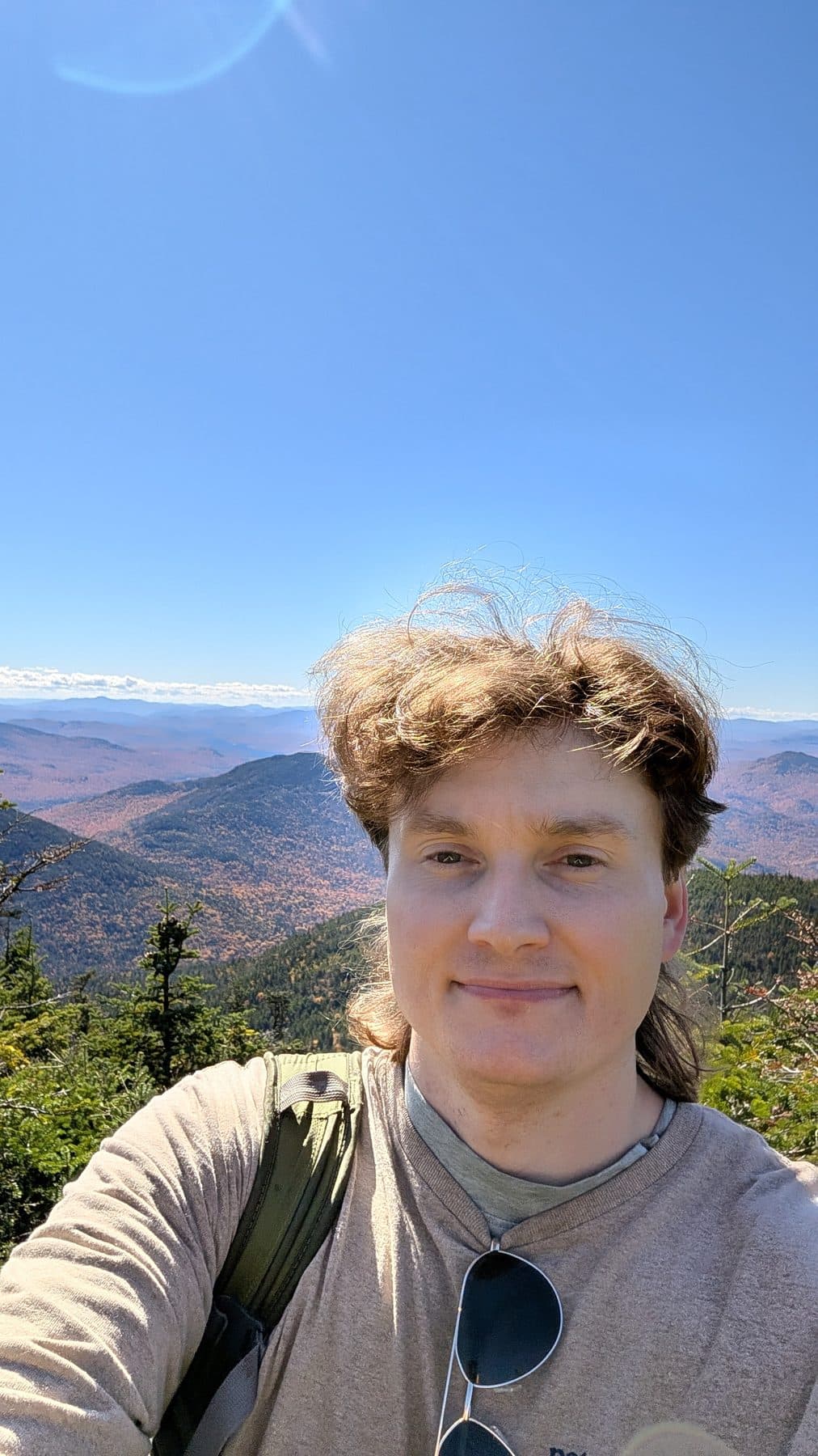 Clark on a windy summit with miles of autumn mountains behind him.